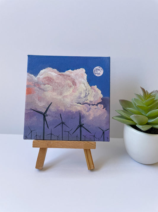 Cloud painting on small wooden easel next to fake plant