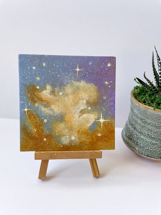 Mini painting of a pink and gold nebula on a small wooden easel