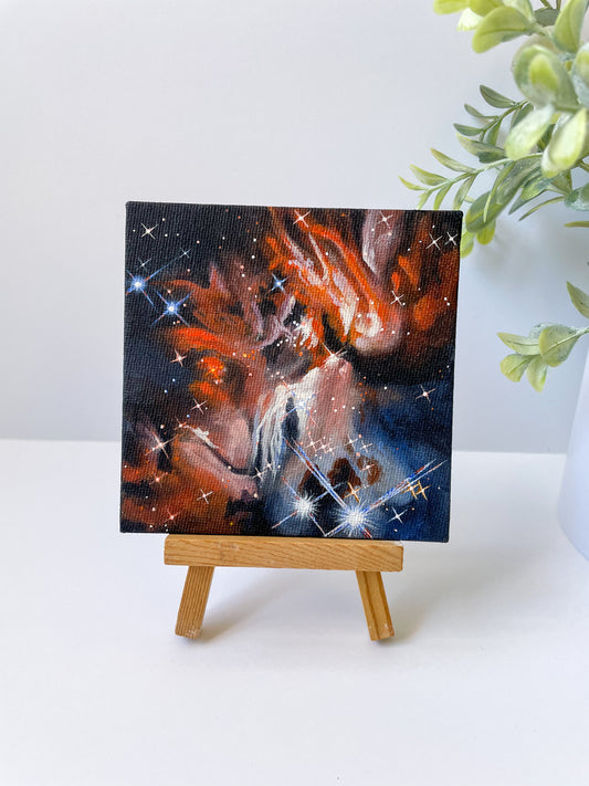 Mini orange, cream, and blue nebula painting on a small wooden easel