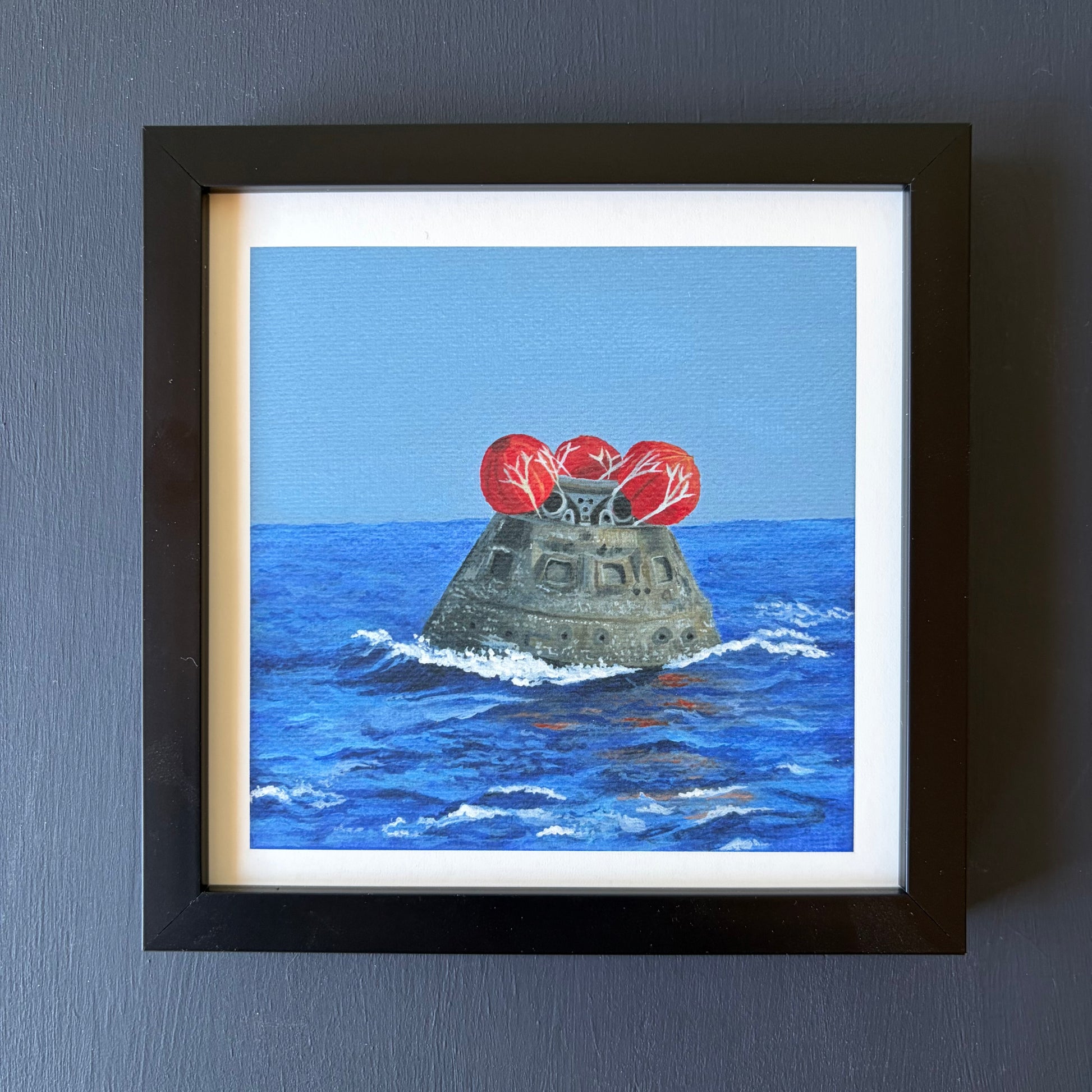 Mini print in black frame of Orion capsule floating in ocean with red balloons on top