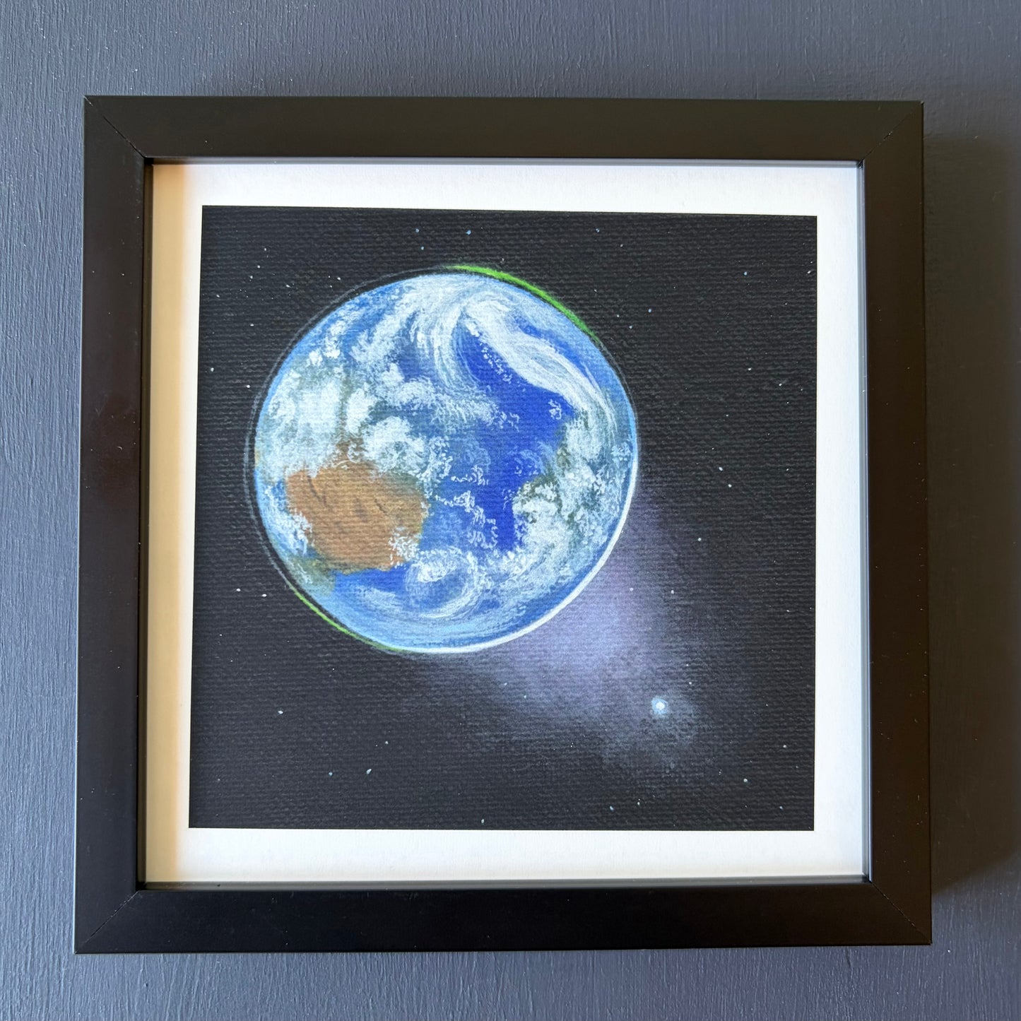 mini print in black frame of Earth from space, Venus in the bottom right, and a black background with a few stars.