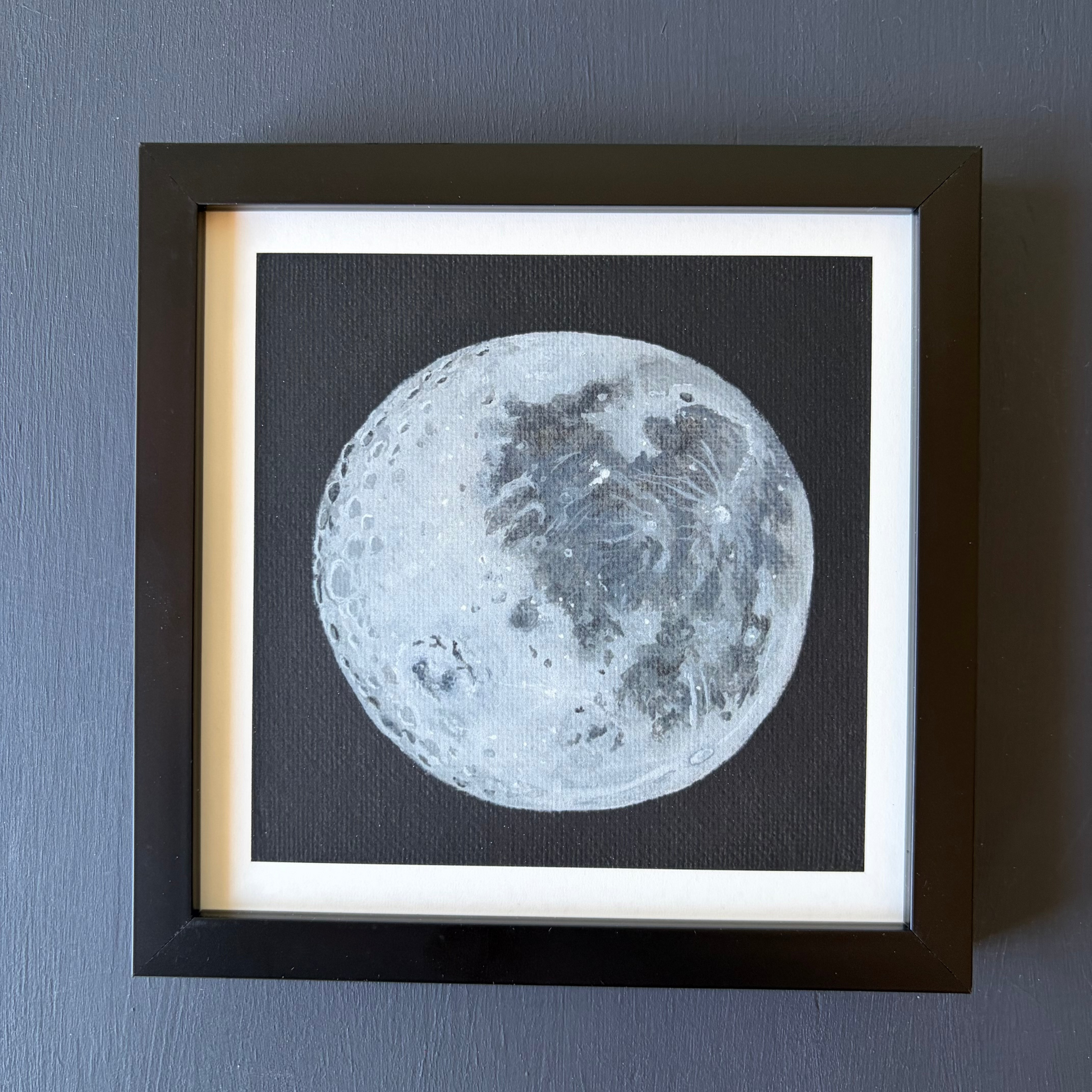 mini print in black frame of the Moon's surface on a black background