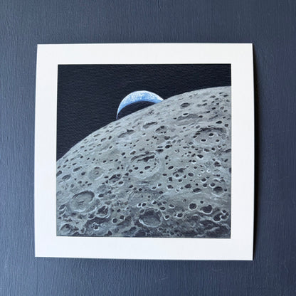 Mini print of the lunar surface in the foreground and a crescent Earth setting behind the Moon