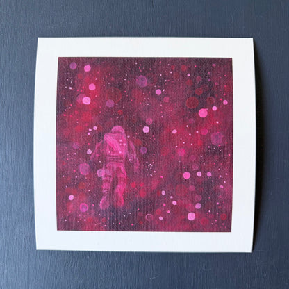 Mini print of astronaut floating surrounded by red and pink bokeh