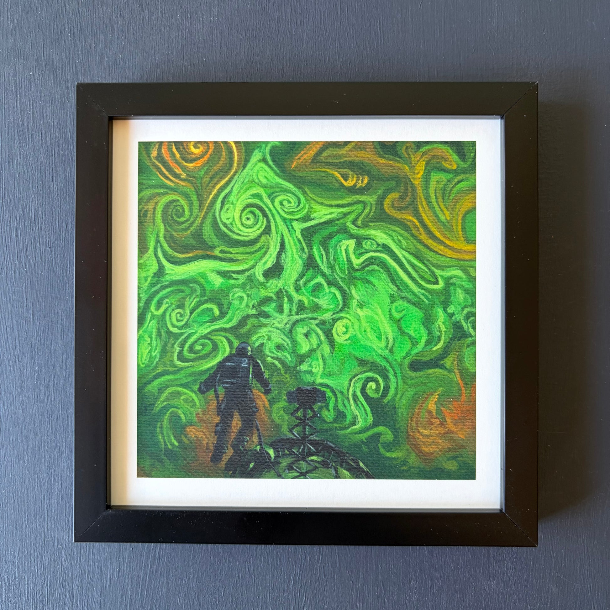 Print in black frame of swirling green and orange clouds. An astronaut floats above a spaceship at the bottom of the piece.