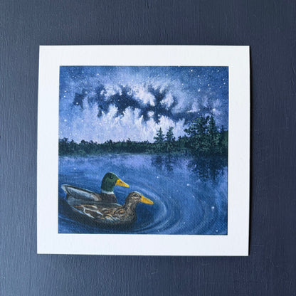 Mini print of two ducks swimming on a lake under a starry night sky with trees in the background.