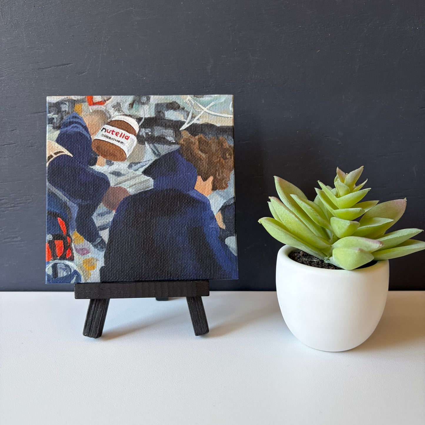 mini painting on easel with Nutella jar in foreground and Artemis astronauts in the background