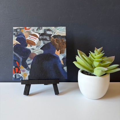 mini painting on easel with Nutella jar in foreground and Artemis astronauts in the background
