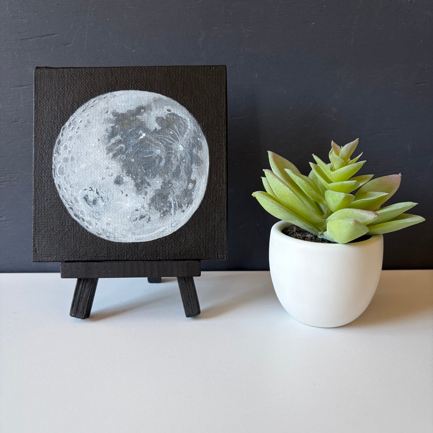 mini painting on easel of the Moon's surface on a black background