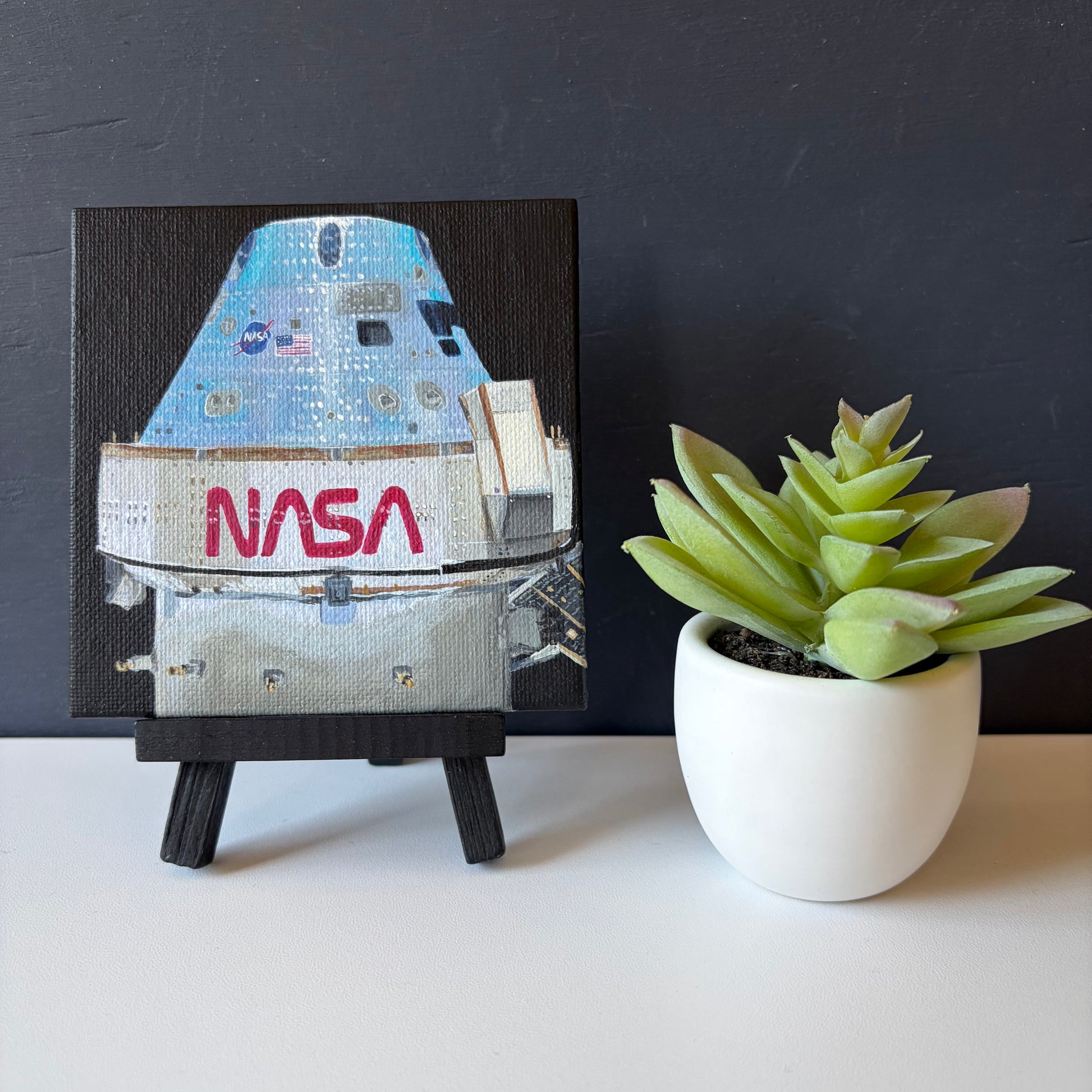 mini painting on easel of Orion capsule  on a black background