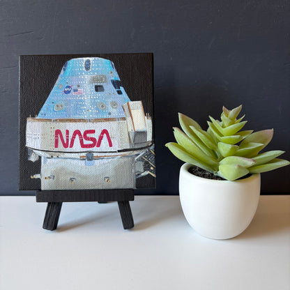 mini painting on easel of Orion capsule  on a black background