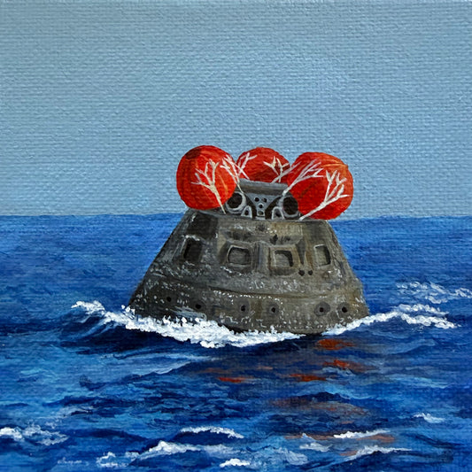 Close up of mini painting of Orion capsule floating in ocean with red balloons on top