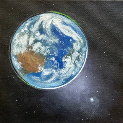 Close up of mini painting of Earth from space, Venus in the bottom right, and a black background with a few stars.