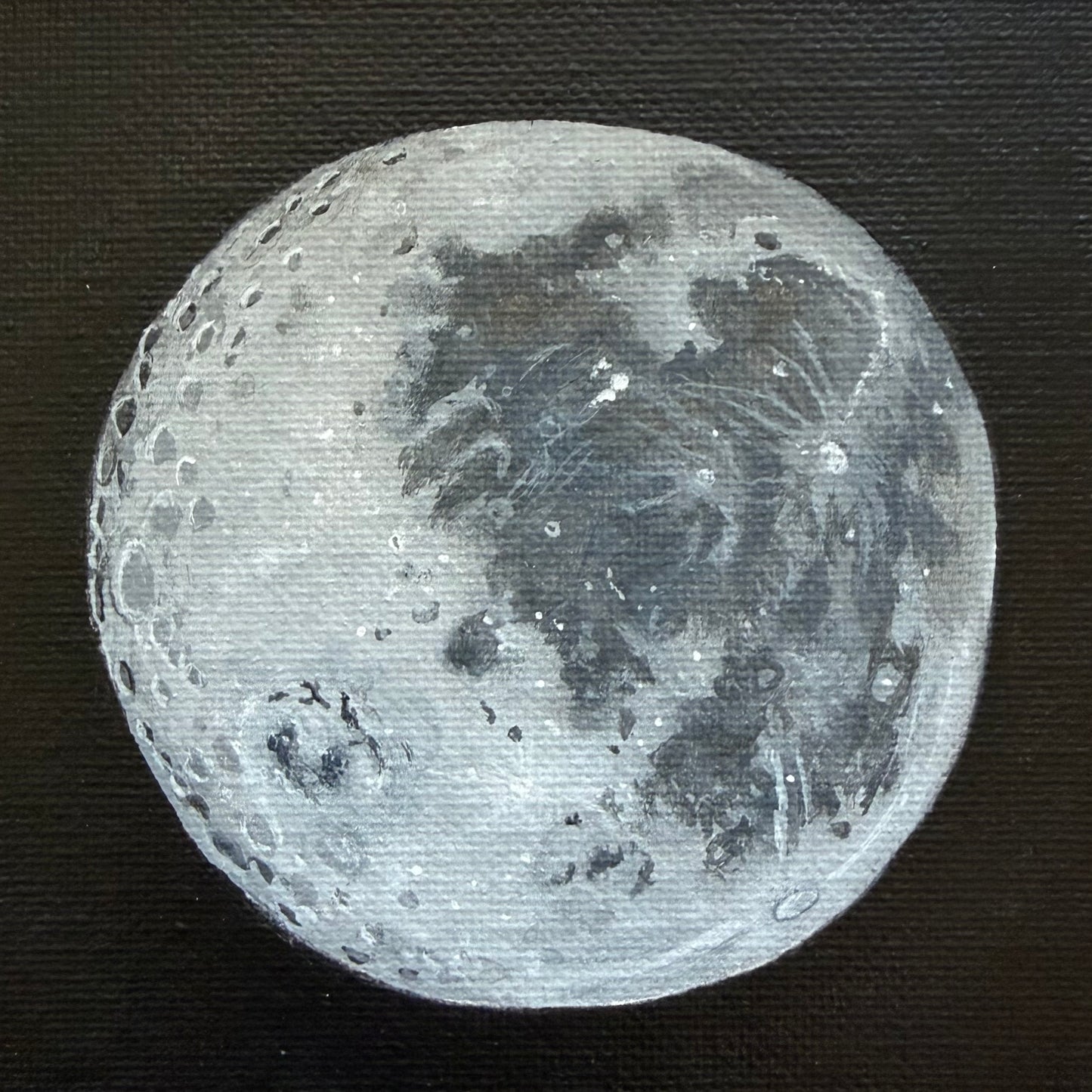 Close up of mini painting of the Moon's surface on a black background