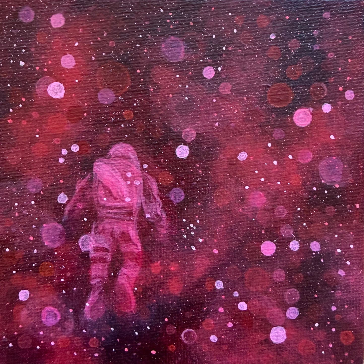 Mini painting close up of an astronaut floating surrounded by red and pink bokeh 