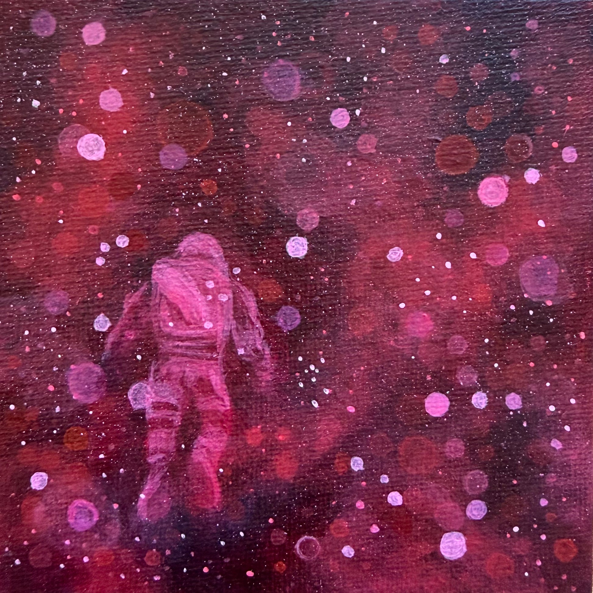 Mini painting close up of an astronaut floating surrounded by red and pink bokeh 
