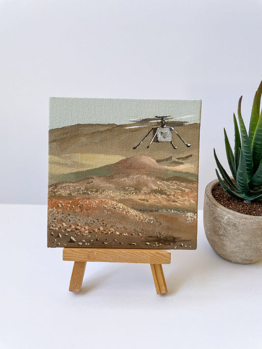 Mini painting of Ingenuity hovering on Mars sitting on small wooden easel
