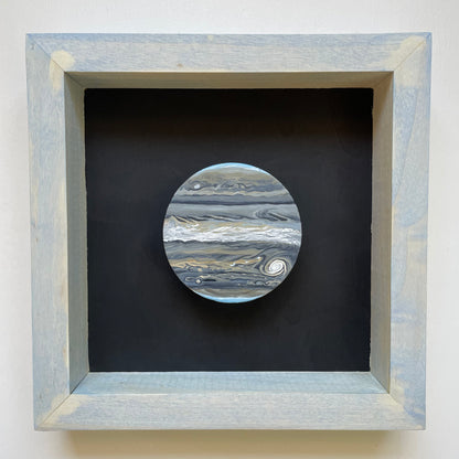 Clay disk painted like Jupiter in infrared in light blue shadowbox frame with black background