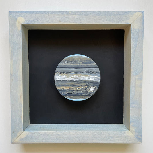 Clay disk painted like Jupiter in infrared in light blue shadowbox frame with black background