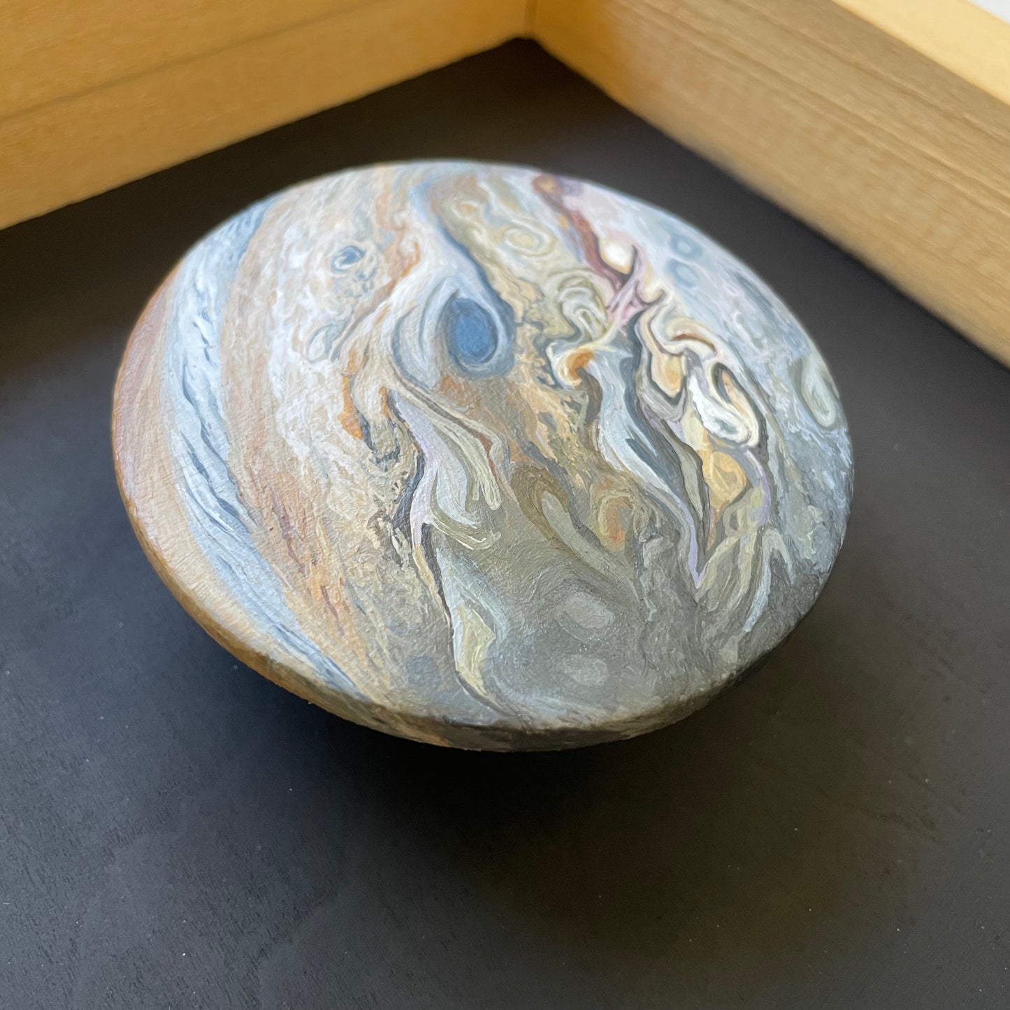 Close up of clay disk painted like Jupiter floating in the frame