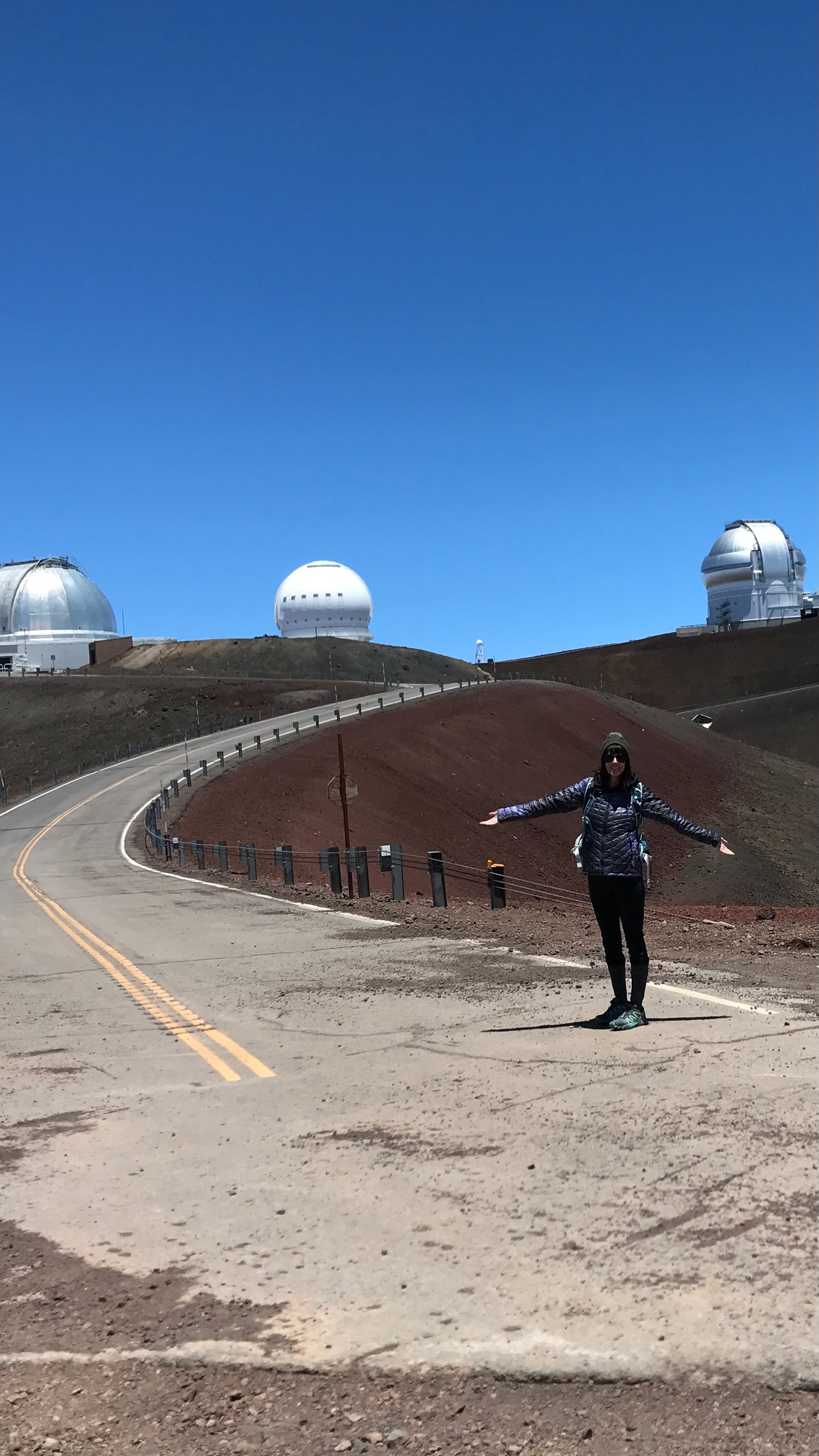 Laci standing at the top of Mauna Kea in Hawaii with telescopes in the background