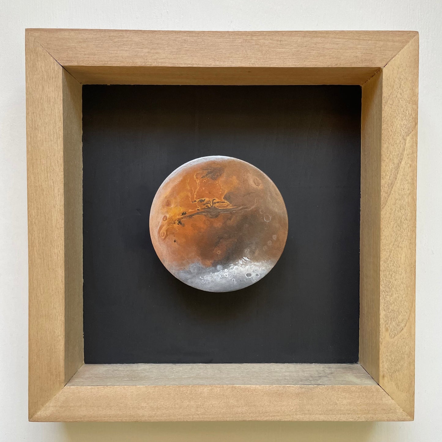 Clay disk painted like Mars in brown stained shadowbox with black background 