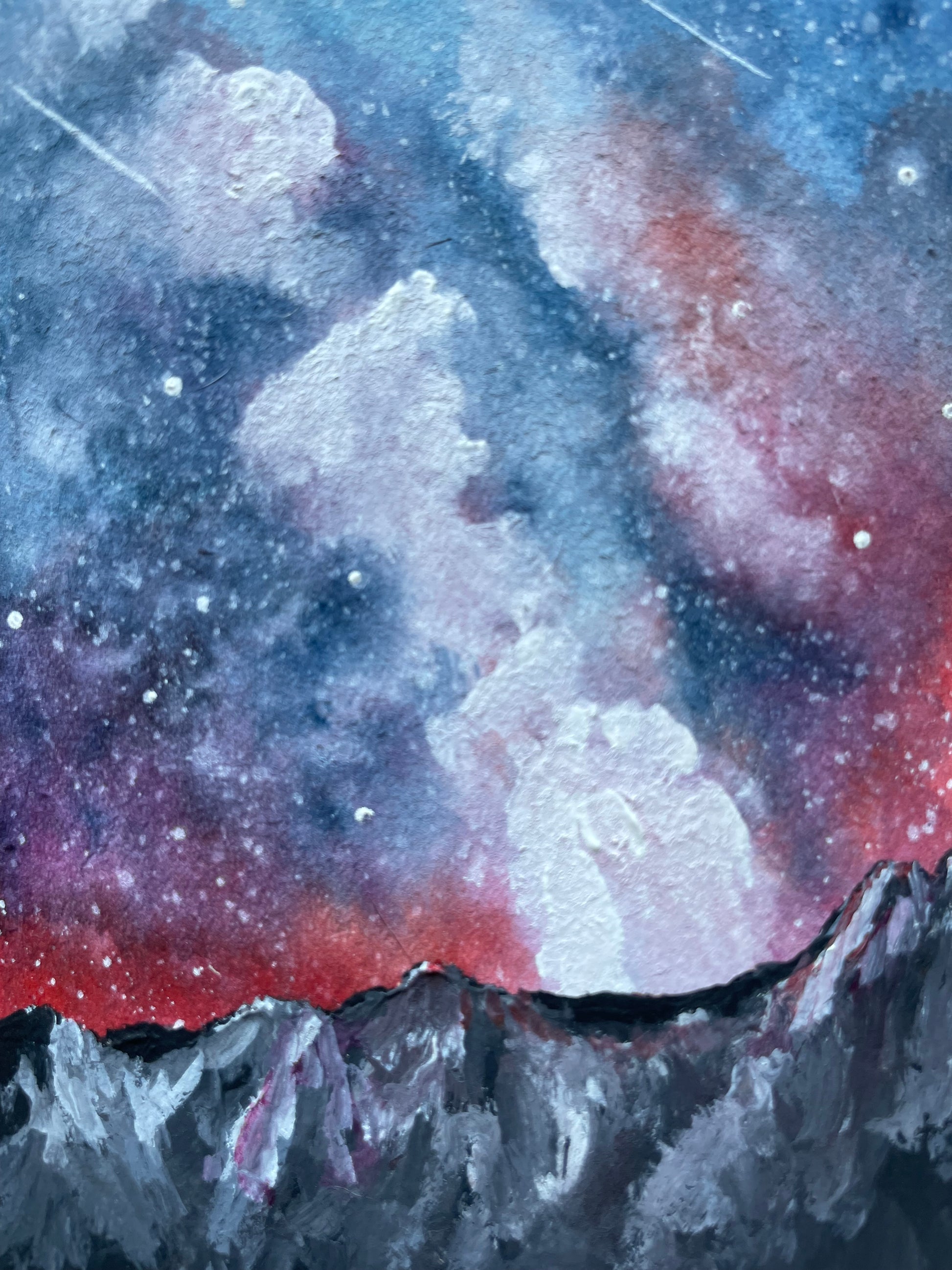 Milky Way painting with bright reddish pink, purple, and blue above grey mountains