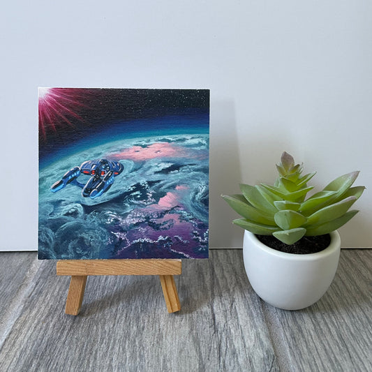 Mini print of starship in orbit of exoplanet. The print is sitting on an easel next to fake plant.