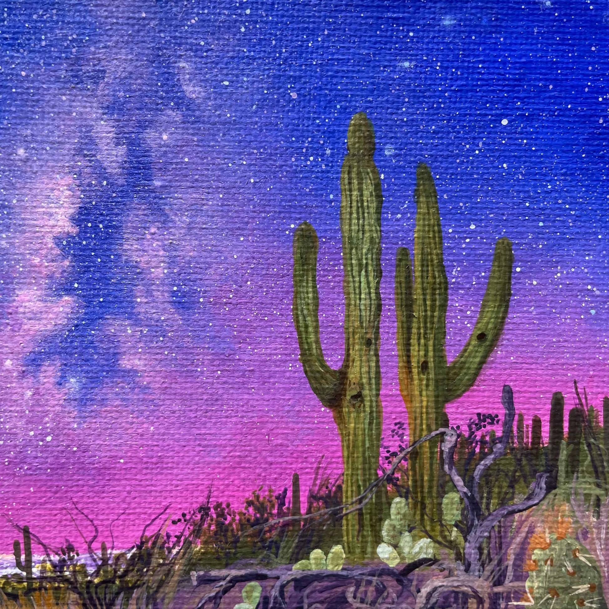 Mini painting of Milky Way in blue, purple, and pink on left side. Two tall saguaros are in the center foreground. Desert foliage is at an angle across the bottom.