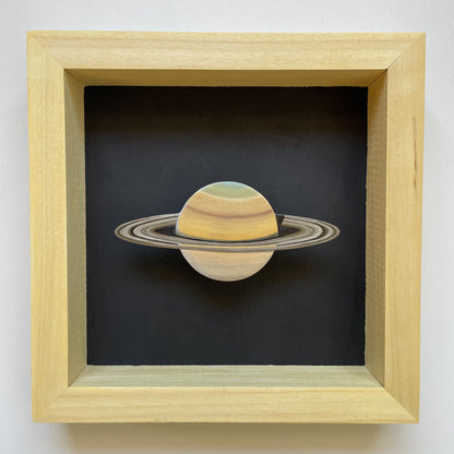 Clay Saturn mounted in yellow shadowbox frame with black background